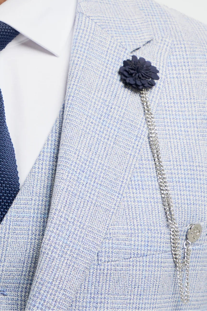 Moški v svetlo sivi obleki z mornarsko modro kravato in cvetlično iglo na belem ozadju